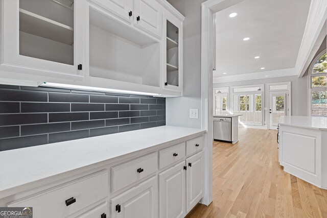 kitchen featuring crown molding, light hardwood / wood-style flooring, white cabinetry, tasteful backsplash, and stainless steel dishwasher