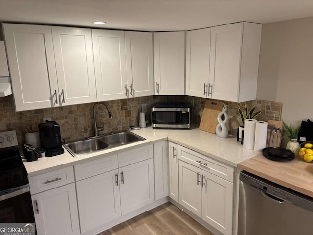 kitchen with sink, white cabinetry, tasteful backsplash, light hardwood / wood-style flooring, and stainless steel appliances