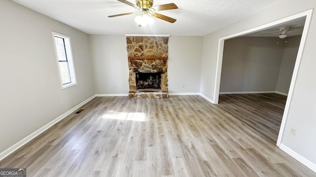 unfurnished living room featuring ceiling fan, a fireplace, and light hardwood / wood-style flooring