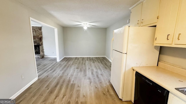 kitchen with ceiling fan, dishwasher, white refrigerator, a textured ceiling, and a stone fireplace