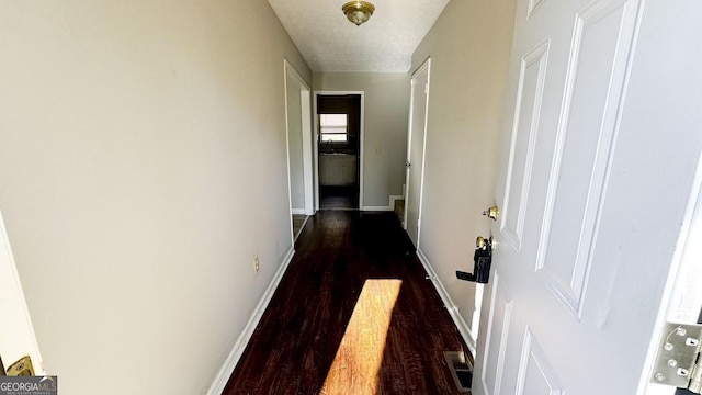 hall with baseboards, dark wood finished floors, visible vents, and a textured ceiling
