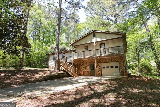 chalet / cabin featuring covered porch, a garage, stone siding, and driveway