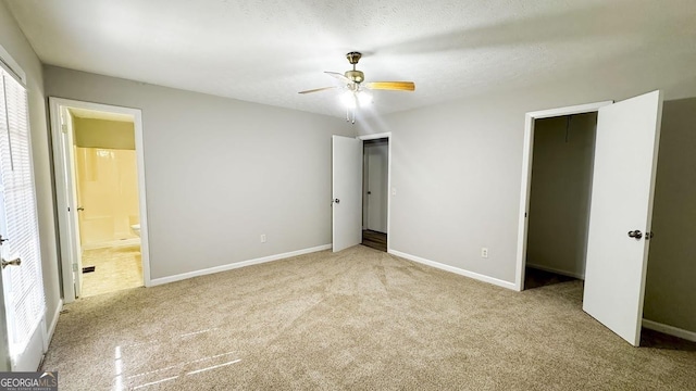 unfurnished bedroom featuring ceiling fan, ensuite bath, light colored carpet, and a textured ceiling