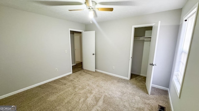 unfurnished bedroom featuring ceiling fan, light colored carpet, a closet, and a textured ceiling