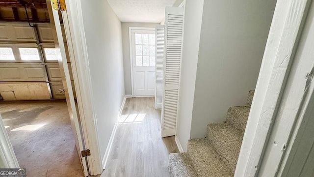 corridor with a textured ceiling and light hardwood / wood-style flooring