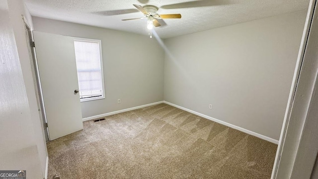 empty room with a textured ceiling, carpet, visible vents, a ceiling fan, and baseboards
