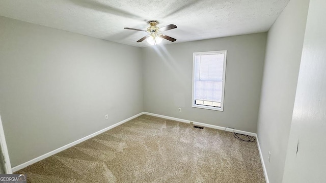 carpeted spare room with baseboards, visible vents, ceiling fan, and a textured ceiling