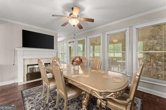 dining room featuring a fireplace, ornamental molding, dark hardwood / wood-style floors, and ceiling fan