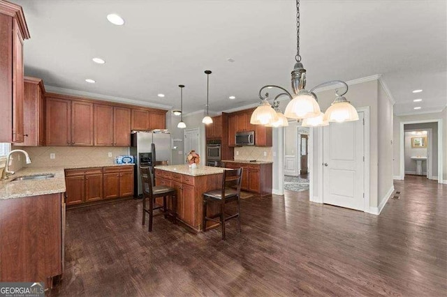 kitchen with sink, a breakfast bar area, hanging light fixtures, stainless steel appliances, and a center island