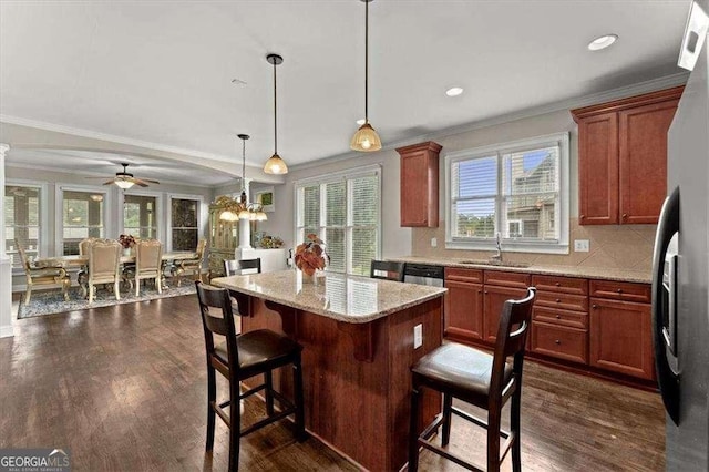 kitchen with appliances with stainless steel finishes, a breakfast bar area, dark hardwood / wood-style flooring, hanging light fixtures, and light stone counters