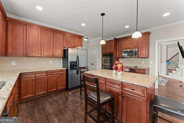 kitchen featuring light stone counters, crown molding, decorative light fixtures, appliances with stainless steel finishes, and a kitchen breakfast bar