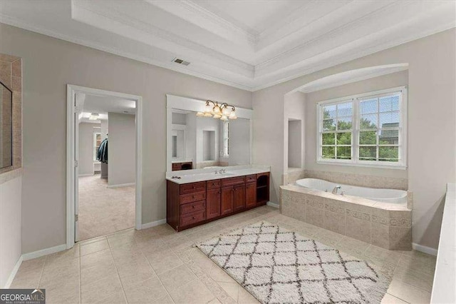 bathroom with a relaxing tiled tub, vanity, a tray ceiling, and ornamental molding