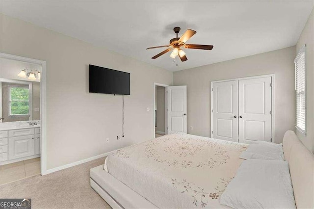 carpeted bedroom with multiple windows, ensuite bath, sink, and a closet