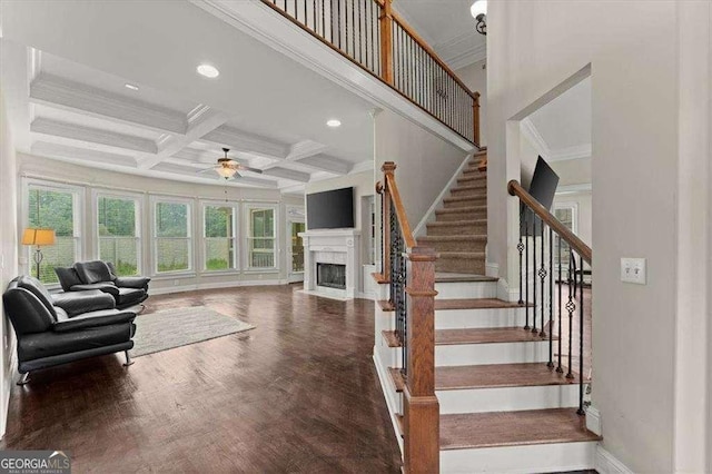 stairway featuring wood-type flooring, ornamental molding, coffered ceiling, ceiling fan, and beam ceiling