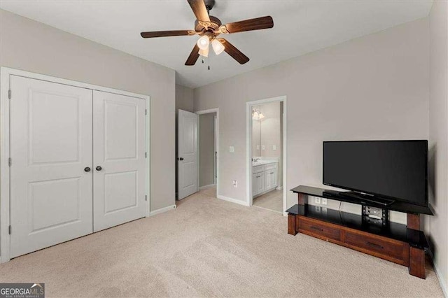 bedroom featuring ensuite bath, light carpet, ceiling fan, and a closet