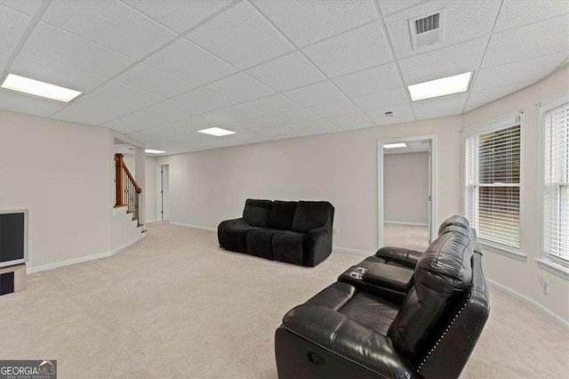 living room with a paneled ceiling and light colored carpet