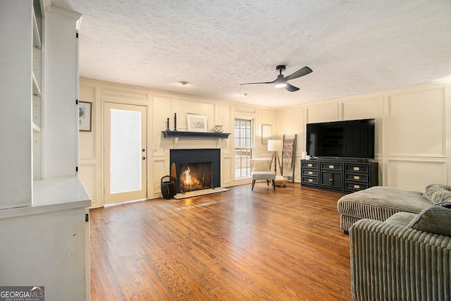 living room with hardwood / wood-style flooring, a textured ceiling, and ceiling fan