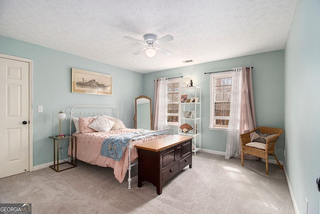 bedroom featuring light carpet, ceiling fan, and a textured ceiling