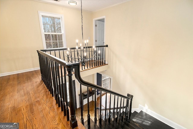 stairs featuring a notable chandelier, crown molding, and hardwood / wood-style floors