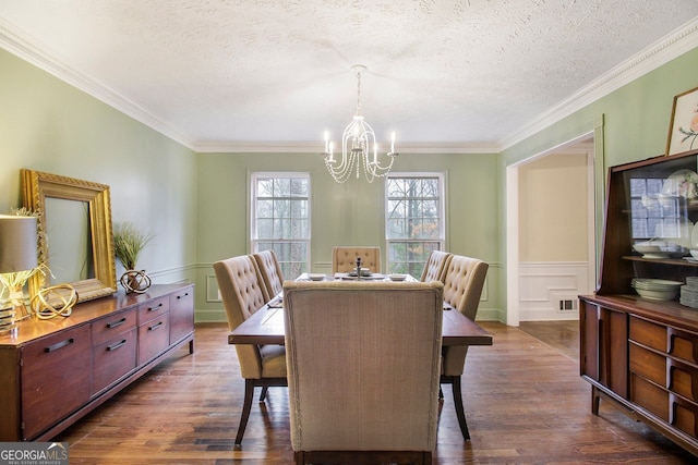 dining space with ornamental molding, dark hardwood / wood-style flooring, a textured ceiling, and a notable chandelier