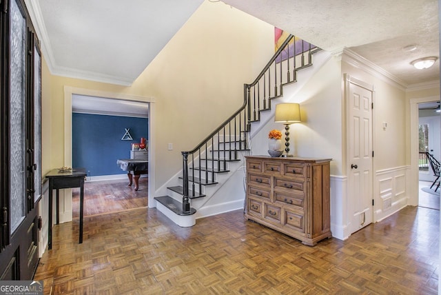 foyer entrance featuring ornamental molding, dark parquet floors, and a textured ceiling