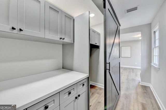 interior space with light hardwood / wood-style flooring, a barn door, and gray cabinets