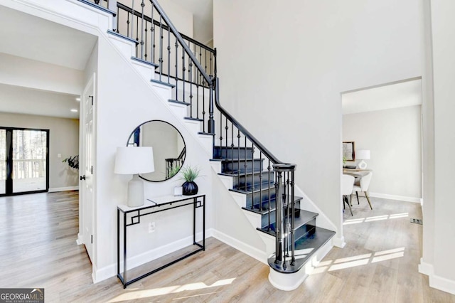 stairway featuring a high ceiling and wood-type flooring