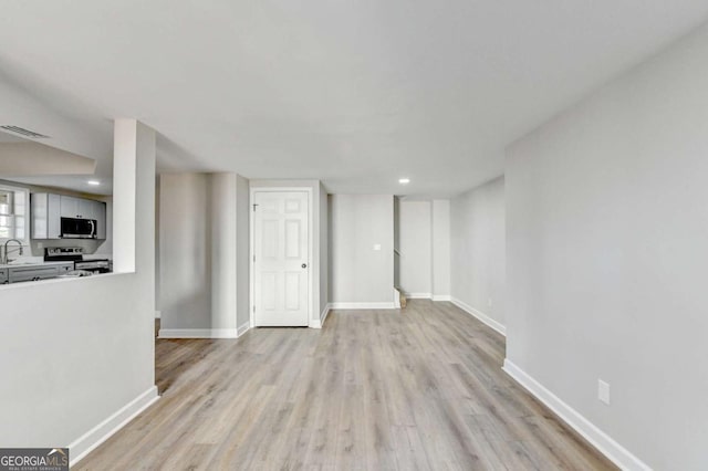 unfurnished living room with light hardwood / wood-style floors and sink