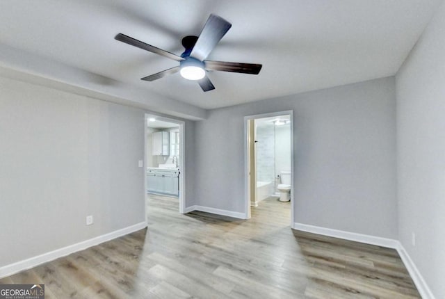 empty room featuring sink, ceiling fan, and light wood-type flooring