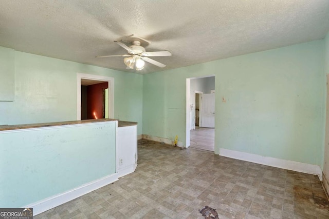 empty room with ceiling fan and a textured ceiling