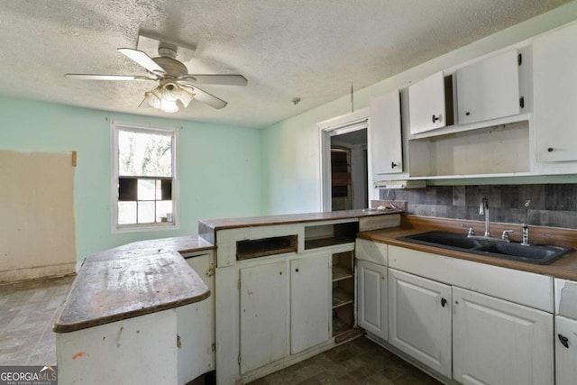 kitchen with white cabinetry, ceiling fan, sink, and a textured ceiling