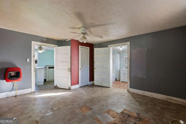 unfurnished bedroom with heating unit, ceiling fan, ensuite bath, and a textured ceiling