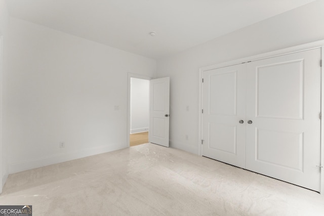 unfurnished bedroom featuring light carpet and a closet