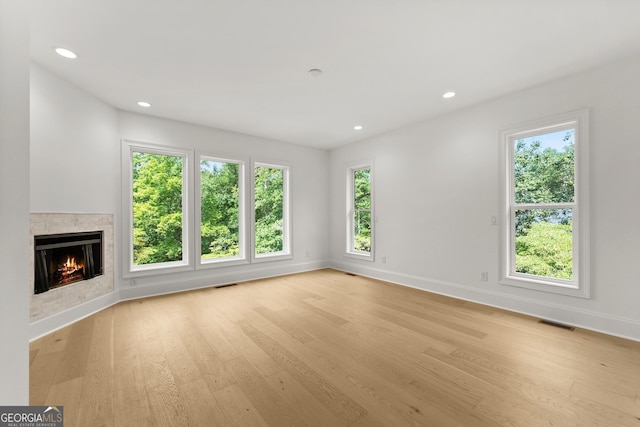 unfurnished living room with a tiled fireplace and light hardwood / wood-style floors