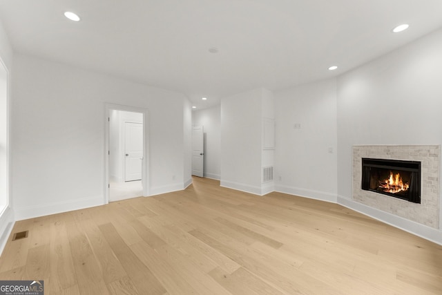 unfurnished living room featuring a fireplace and light hardwood / wood-style floors