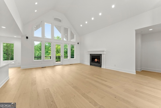 unfurnished living room featuring high vaulted ceiling and light wood-type flooring