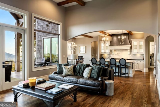 living room featuring an inviting chandelier, arched walkways, dark wood finished floors, and beam ceiling