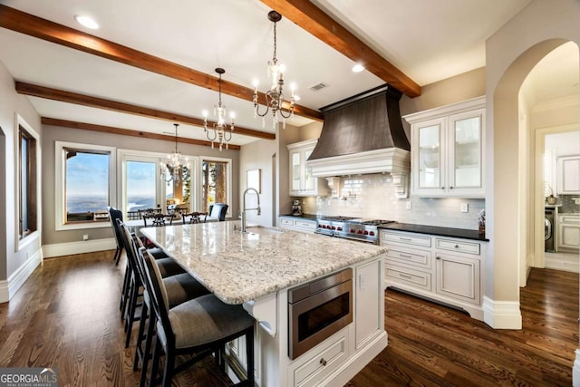 kitchen featuring a sink, white cabinetry, appliances with stainless steel finishes, custom exhaust hood, and glass insert cabinets