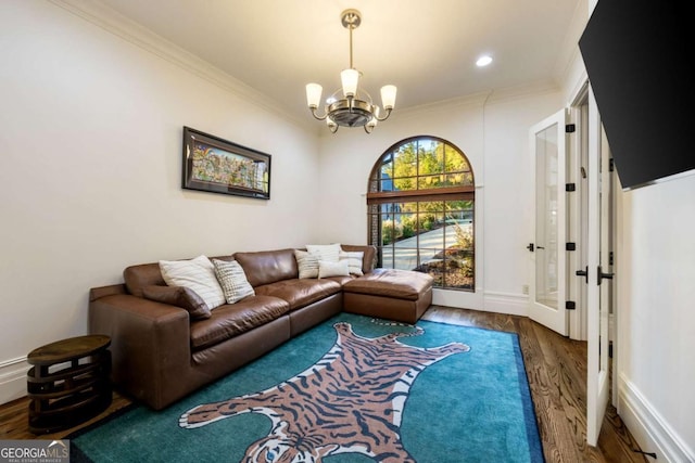 living area with a notable chandelier, baseboards, dark wood finished floors, and crown molding