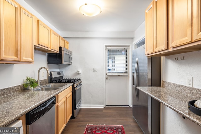 kitchen with dark wood-type flooring, sink, dark stone counters, light brown cabinets, and stainless steel appliances