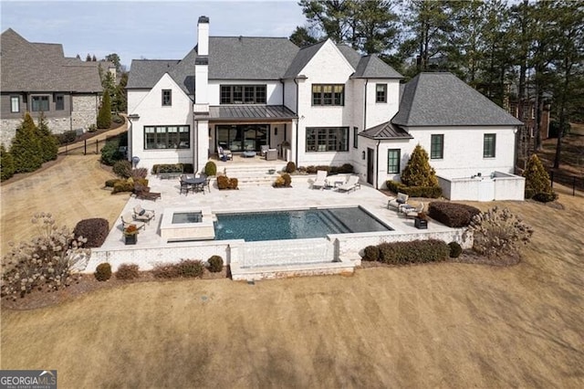 back of property featuring a yard, a patio area, and an outdoor fire pit