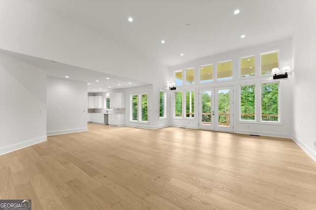 unfurnished living room featuring a towering ceiling and light hardwood / wood-style flooring