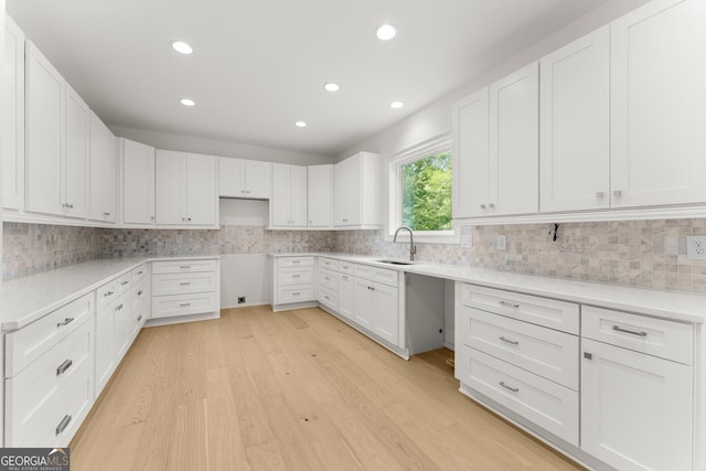 kitchen featuring white cabinetry, sink, backsplash, and light hardwood / wood-style flooring