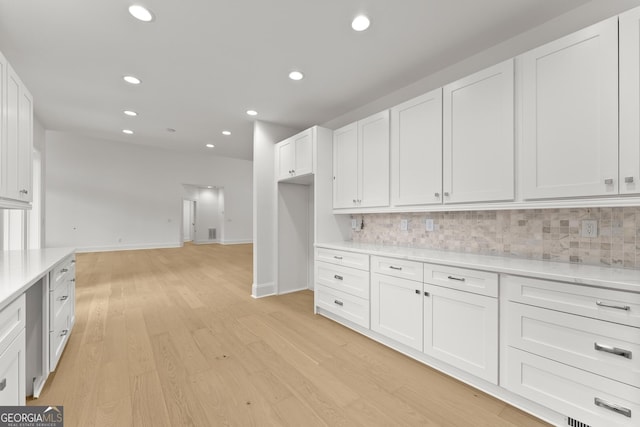 kitchen featuring light hardwood / wood-style floors, decorative backsplash, and white cabinets