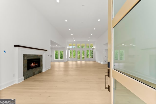 unfurnished living room featuring a towering ceiling and light hardwood / wood-style flooring