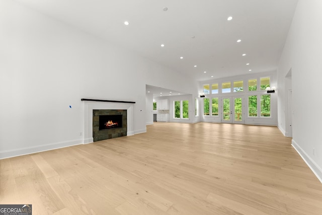 unfurnished living room with a towering ceiling and light hardwood / wood-style floors