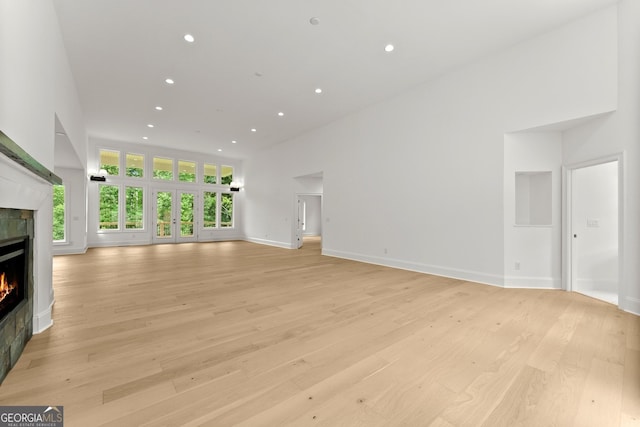 unfurnished living room featuring light hardwood / wood-style flooring and a high ceiling