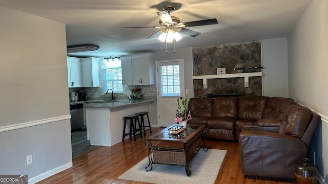 living room with ceiling fan, a fireplace, dark hardwood / wood-style floors, and sink