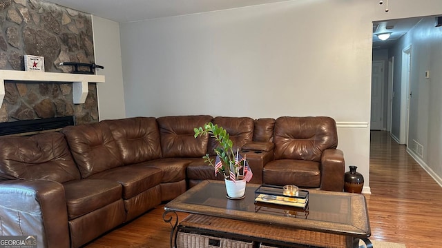 living room featuring a stone fireplace and hardwood / wood-style floors