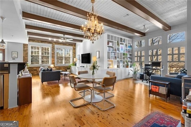 dining room with beam ceiling, ceiling fan with notable chandelier, and light wood-type flooring